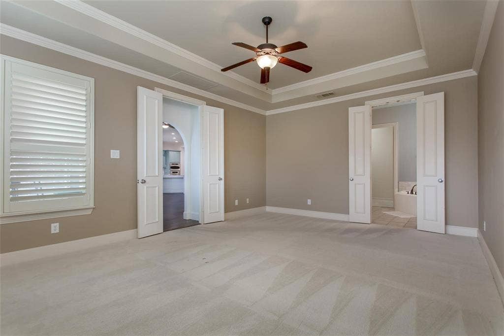 921 Pine Burst Drive, Allen, TX 75013 Spacious room with tray ceiling, crown molding, a ceiling fan, and carpet flooring