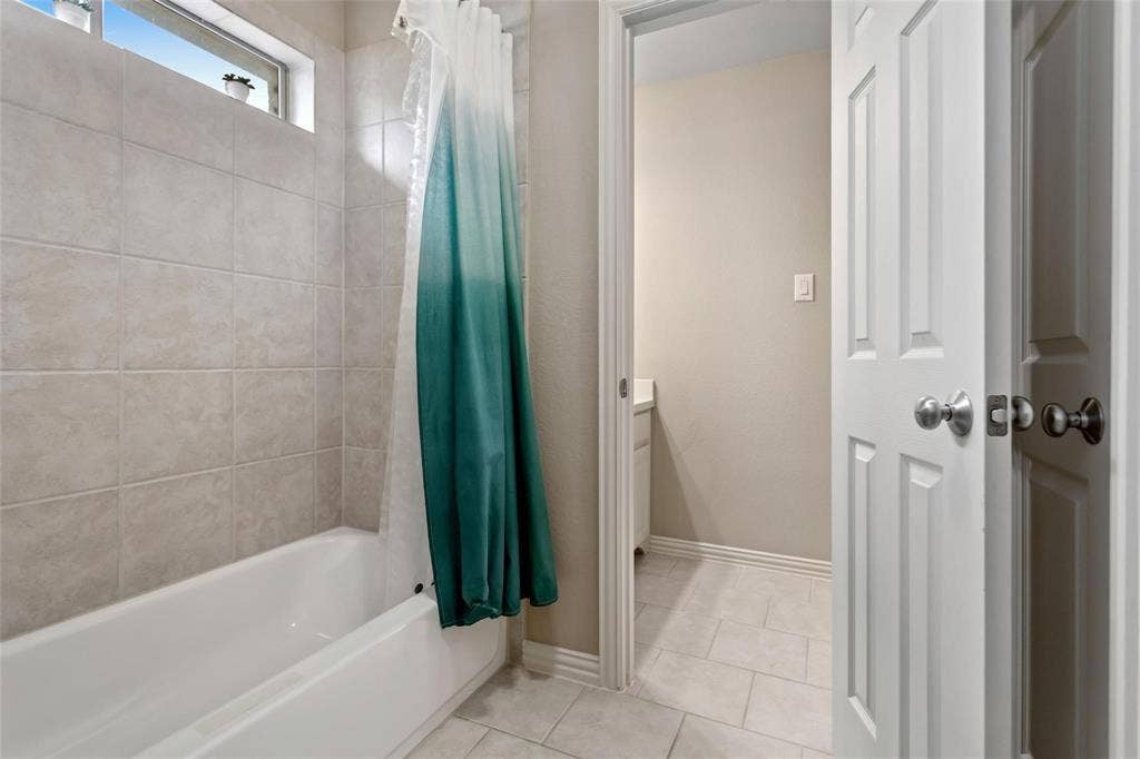 921 Pine Burst Drive, Allen, TX 75013 Bathroom featuring a white bathtub, light-toned tile surround, and an upper transom window