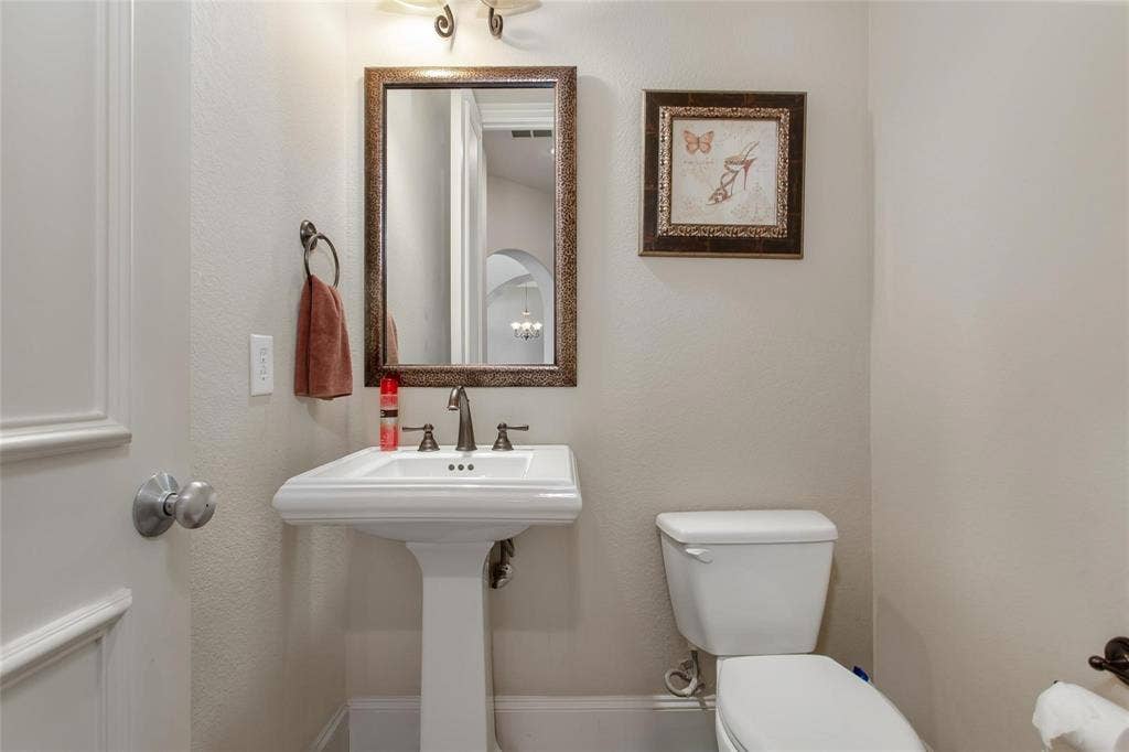 921 Pine Burst Drive, Allen, TX 75013 Pedestal sink with a three-piece bronze-finish faucet, framed mirror, and decorative wall sconce lighting