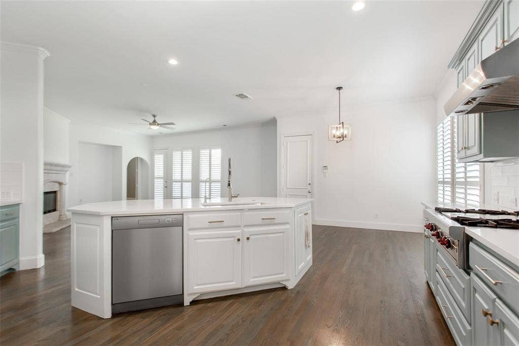 921 Pine Burst Drive, Allen, TX 75013 Spacious kitchen featuring an expansive central island with integrated sink and dishwasher, white cabinetry, light countertops, and dark wood-finish flooring