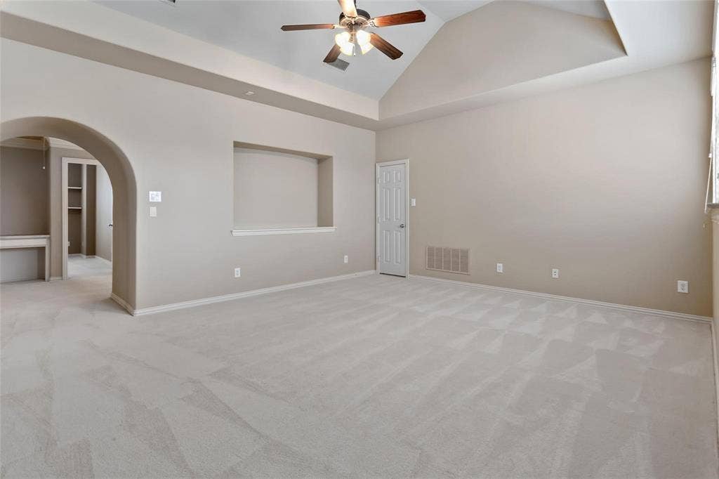 921 Pine Burst Drive, Allen, TX 75013 Spacious room featuring vaulted ceilings, light-toned carpeting, an arched doorway, a built-in niche, and a ceiling fan with integrated lighting