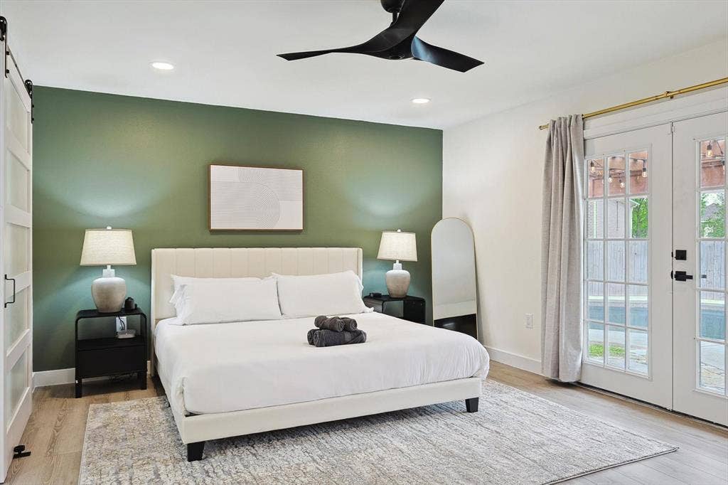 1208 Mayleaf Drive, Irving, TX 75060 Bedroom featuring a distinctive green accent wall and wood-finish flooring
