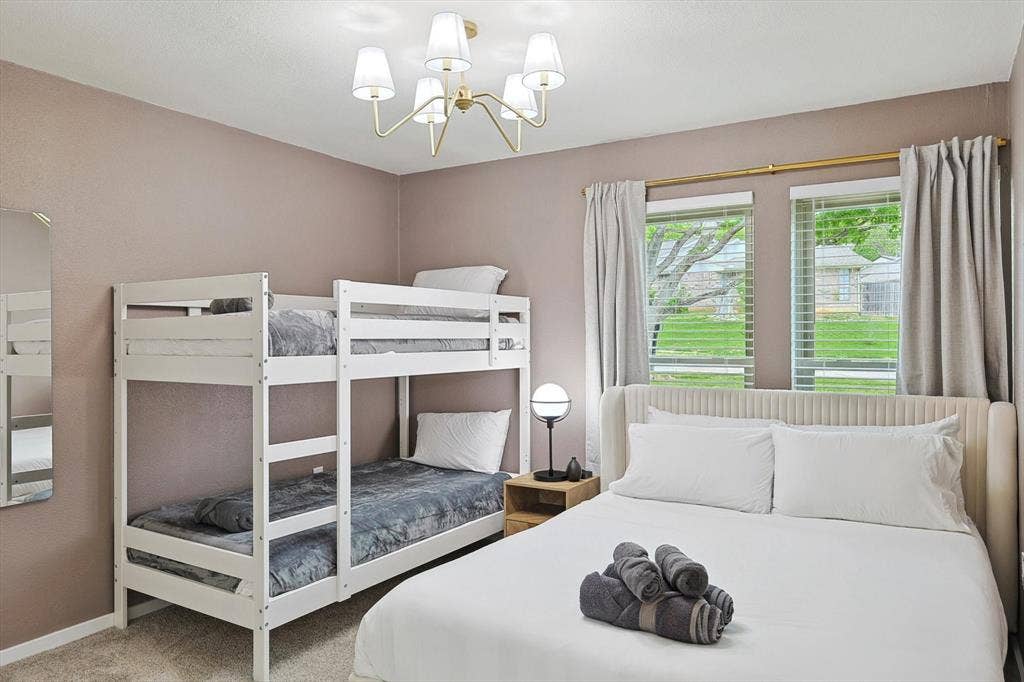 1208 Mayleaf Drive, Irving, TX 75060 Bedroom featuring two window openings with blinds, a white bunk bed frame, a bed with a cream upholstered headboard, a bedside table, and a contemporary ceiling light fixture