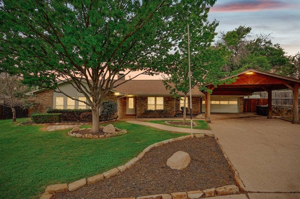 1208 Mayleaf Drive, Irving, TX 75060 Brick exterior featuring a covered carport, two-car garage, and established landscaping