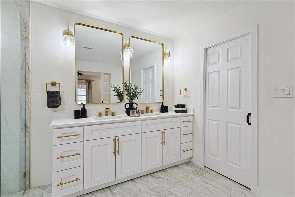1208 Mayleaf Drive, Irving, TX 75060 White dual vanity with quartz countertop, dual gold-framed mirrors, gold-finish hardware, and a six-panel door