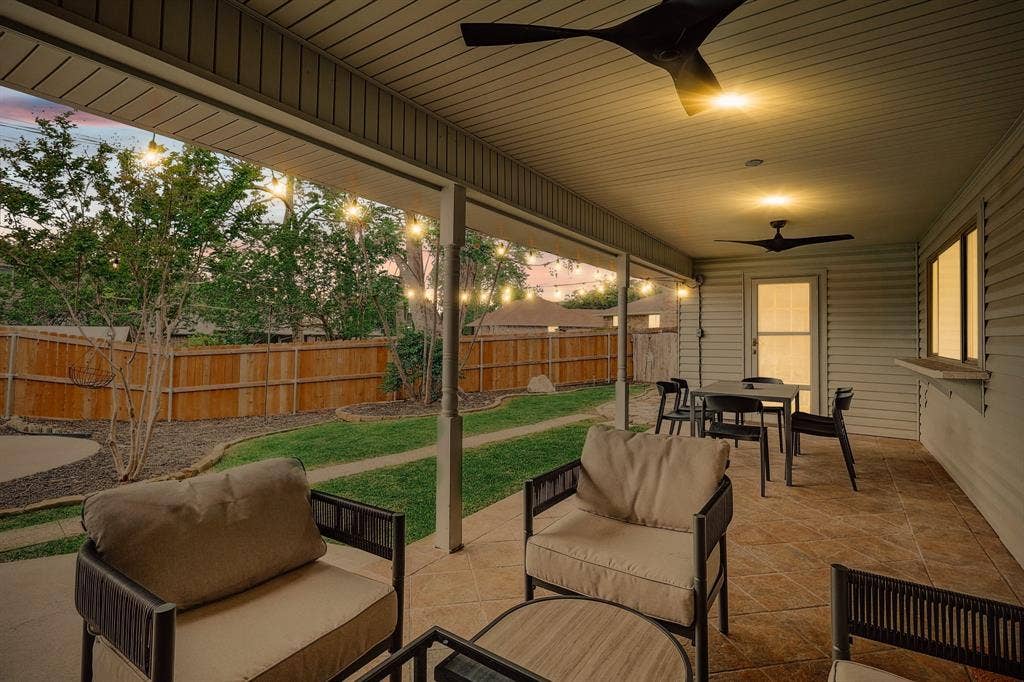 1208 Mayleaf Drive, Irving, TX 75060 Spacious covered patio featuring ceiling fans, string lighting, tiled flooring, wood fence, and a private backyard with mature trees