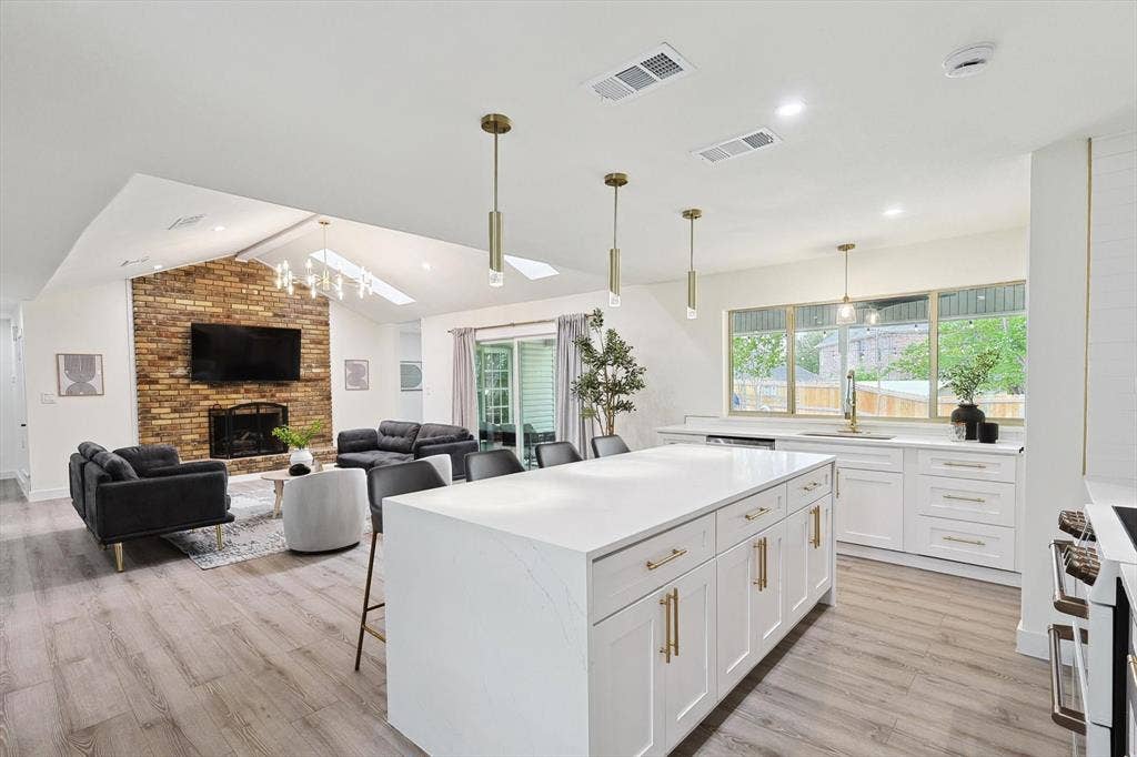 1208 Mayleaf Drive, Irving, TX 75060 Open-concept living area featuring wood-finish flooring, a brick fireplace, and a kitchen island with a quartz countertop