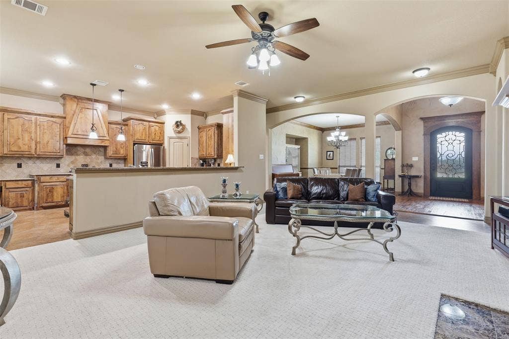 Open-concept living area featuring light-colored carpeting and a ceiling fan