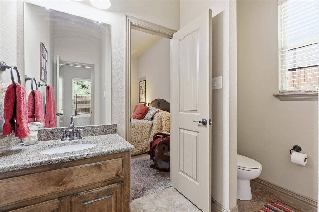 Bathroom vanity featuring a granite countertop with an undermount sink and wood-finish cabinetry
