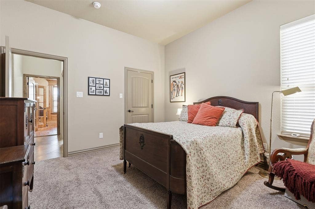 Carpeted bedroom featuring a window with white blinds, neutral wall tones, and a paneled interior door