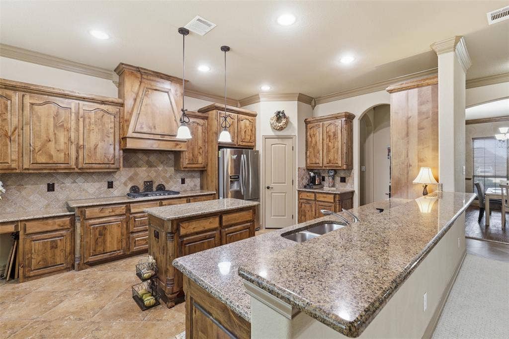 Spacious kitchen featuring extensive wood cabinetry, granite countertops, a central island, stainless steel appliances, and integrated recessed lighting