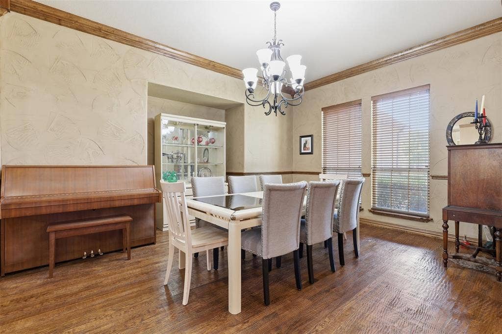 Formal dining area featuring rich wood-finish flooring, textured walls, and decorative crown molding