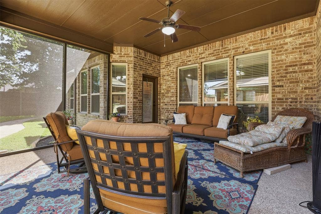Screened-in porch featuring brick walls, a textured ceiling, and a ceiling fan