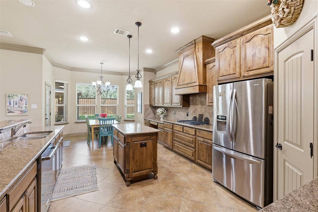 Kitchen featuring wood cabinetry, stainless steel appliances, a center island, and granite countertops