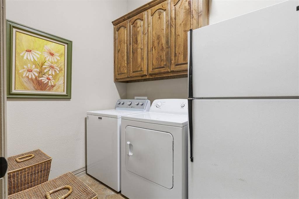 Integrated laundry area featuring wood-finish cabinetry and tile flooring