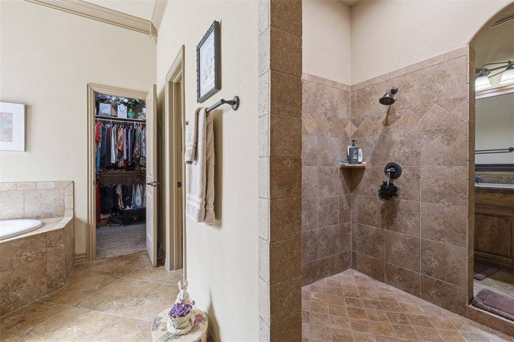 Spacious bathroom featuring a walk-in shower with tile surround and dark bronze fixtures, a built-in corner tub with tile surround, and tile flooring