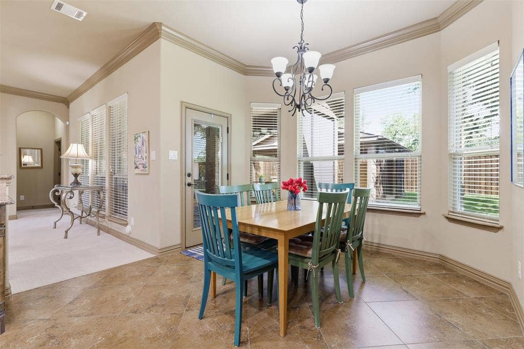 Dining area featuring tile flooring, a chandelier, and multiple windows with blinds