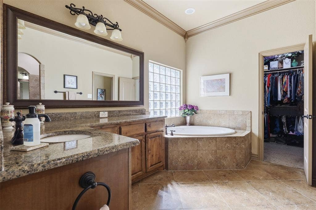 Bathroom featuring a dual vanity with granite countertops, wood-finish cabinetry, and a large framed mirror