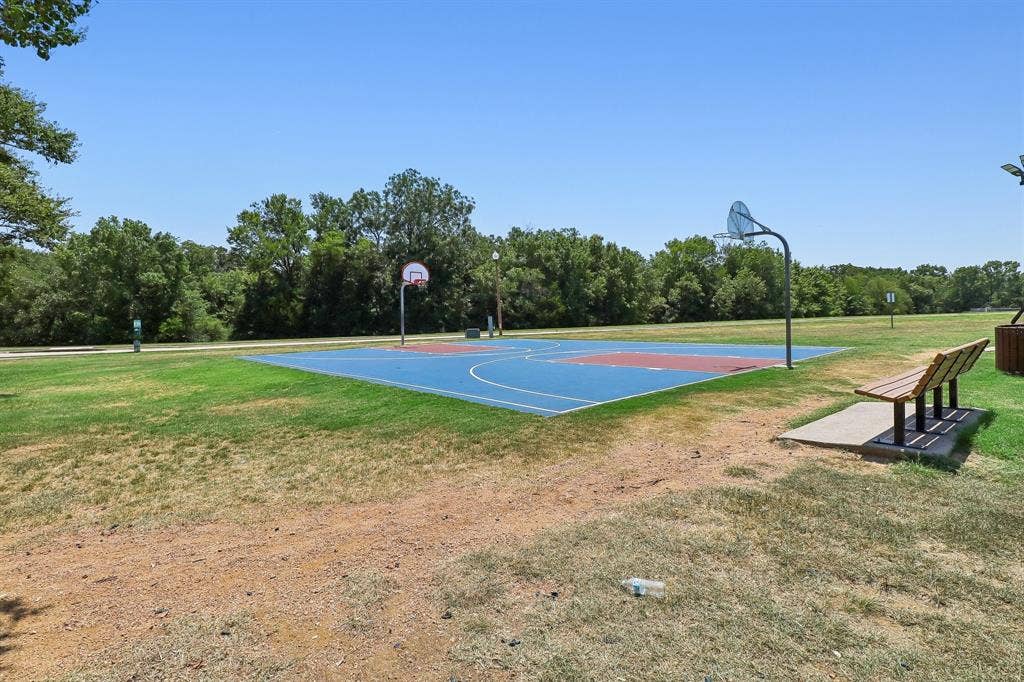 Multi-color basketball court featuring two hoops and a perimeter of green grass