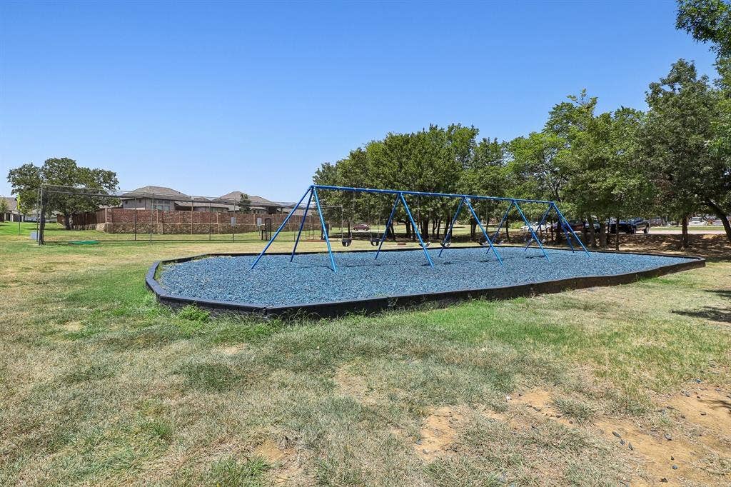 Recreational area featuring a swing set with blue metal framing and a blue rubberized ground surface