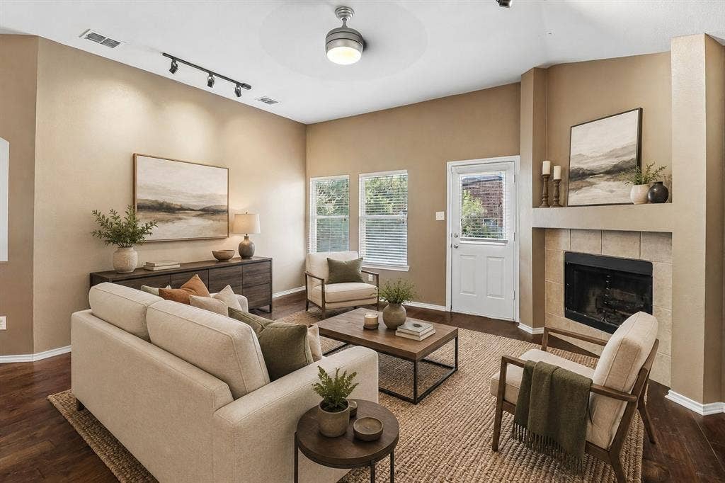 Inviting living area featuring rich wood-finish flooring, a tiled fireplace with mantel, and ample natural light from multiple windows - Virtual Staging