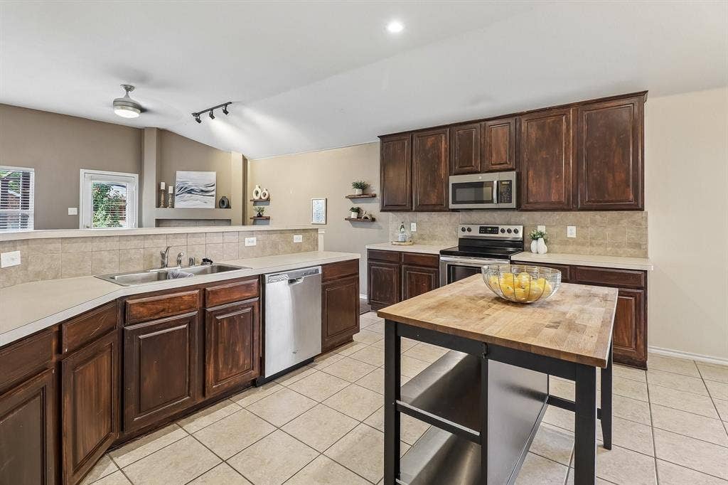 Kitchen featuring dark wood cabinetry, light-toned countertops, and a tiled backsplash