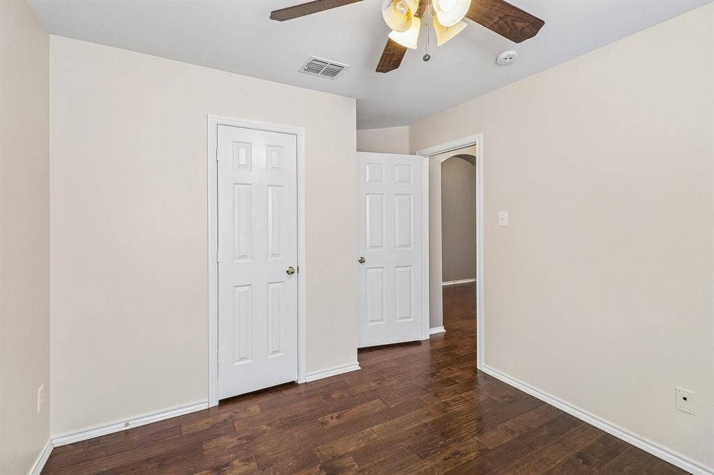 Room featuring dark wood-finish flooring, light-toned walls, and white baseboards