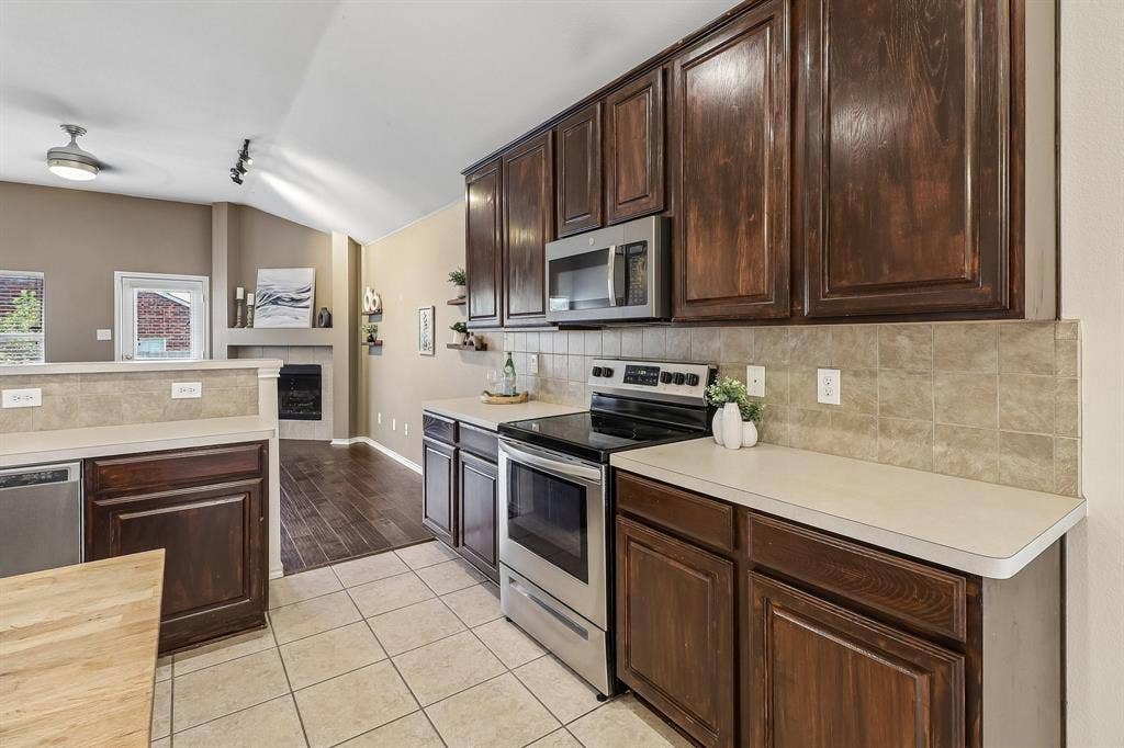Well-appointed kitchen featuring rich wood cabinetry, light-toned countertops, and a tiled backsplash