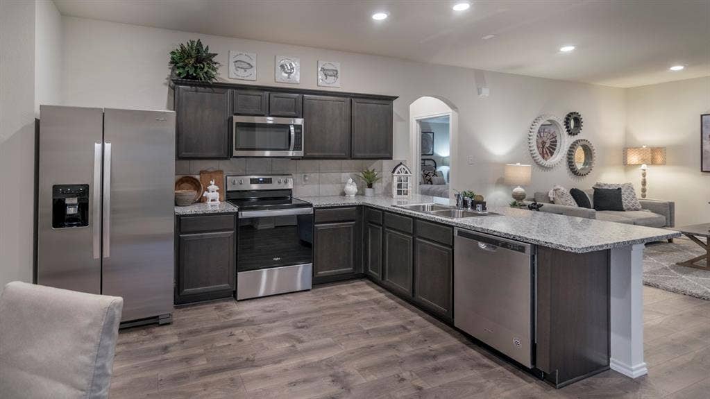 5618 Gannet Place, Crandall, TX 75114 Well-appointed kitchen featuring wood-finish flooring, dark wood cabinetry, a light-toned countertop, and stainless steel appliances
