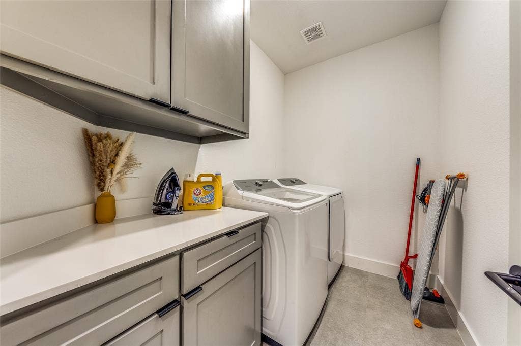1116 Muncie Avenue, Dallas, TX 75212 Dedicated laundry area featuring a light countertop, gray cabinetry with black hardware, and tile flooring