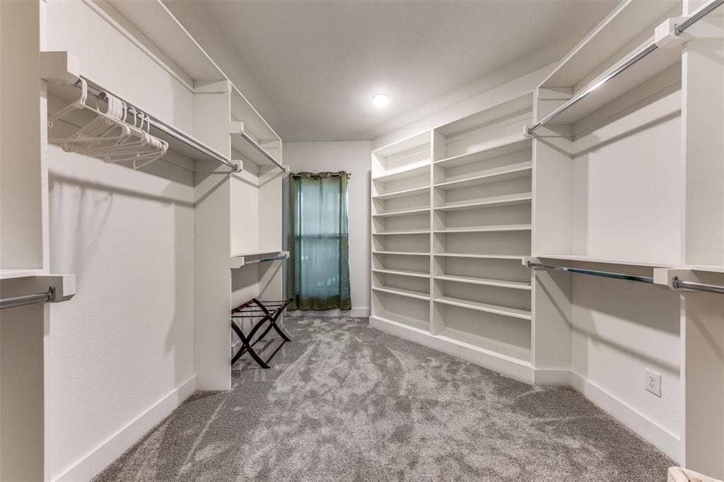 1116 Muncie Avenue, Dallas, TX 75212 Spacious custom closet featuring extensive built-in shelving, multiple hanging rods, and plush gray carpeting