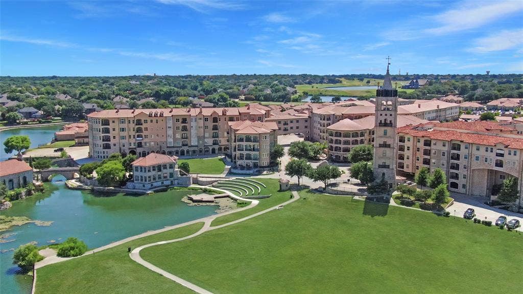 6601 Mediterranean Drive, #6101, McKinney, TX 75072 Expansive green space bordered by a multi-story building complex featuring balconies, red tile roofs, and stone facades