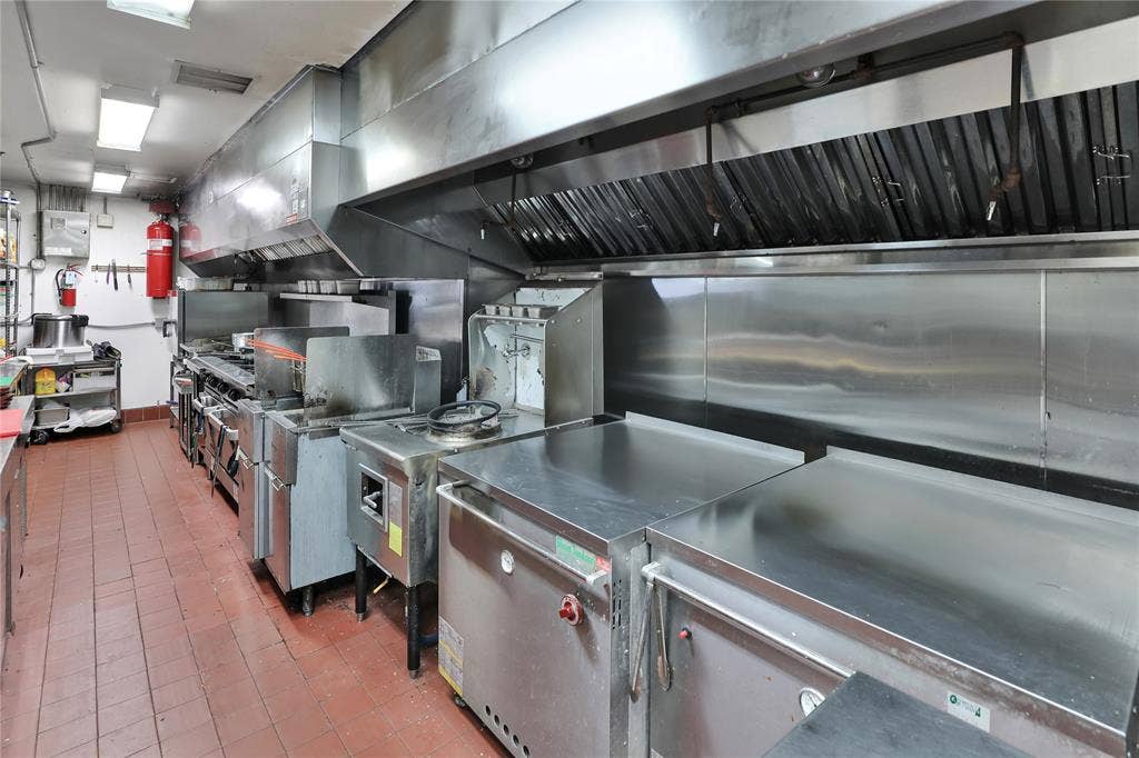 6601 Mediterranean Drive, #6101, McKinney, TX 75072 Commercial kitchen featuring stainless steel equipment, expansive ventilation hoods, and red tile flooring