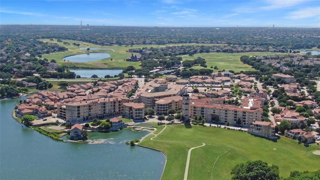 6601 Mediterranean Drive, #6101, McKinney, TX 75072 Aerial overview featuring a community with Mediterranean-style architecture, red tile roofs, and stucco exteriors situated around a body of water