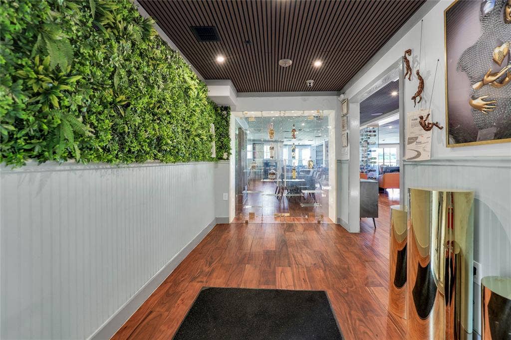 6601 Mediterranean Drive, #6101, McKinney, TX 75072 Entryway featuring a striking green wall installation, wood-finish flooring, white wainscoting, and a slatted ceiling