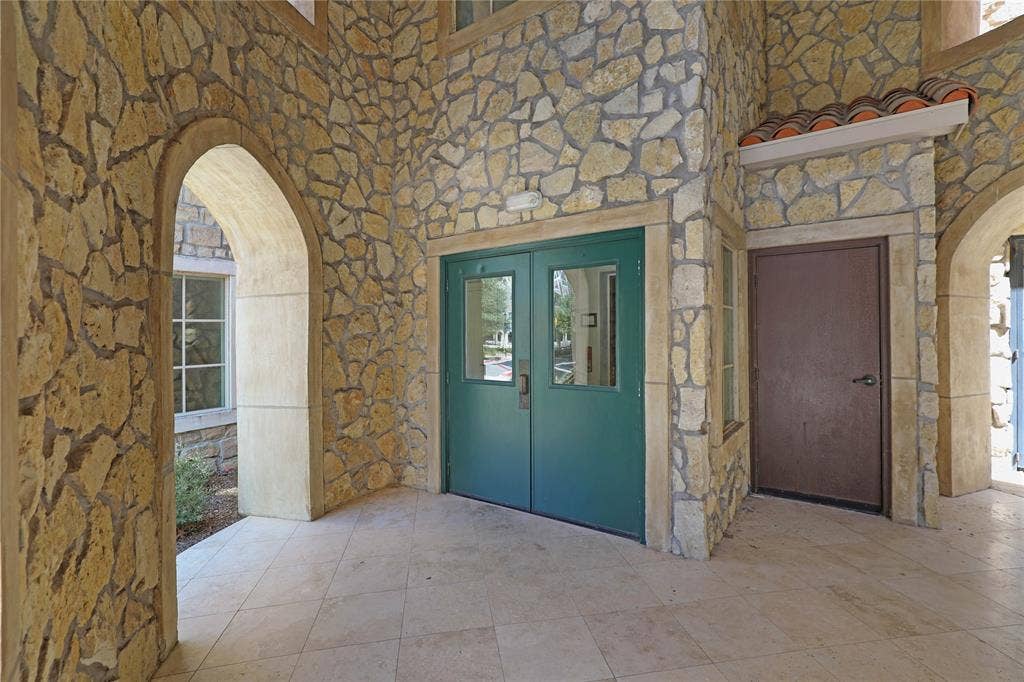 6601 Mediterranean Drive, #6101, McKinney, TX 75072 Exterior stone facade featuring multiple arched entries and a covered patio with tiled flooring