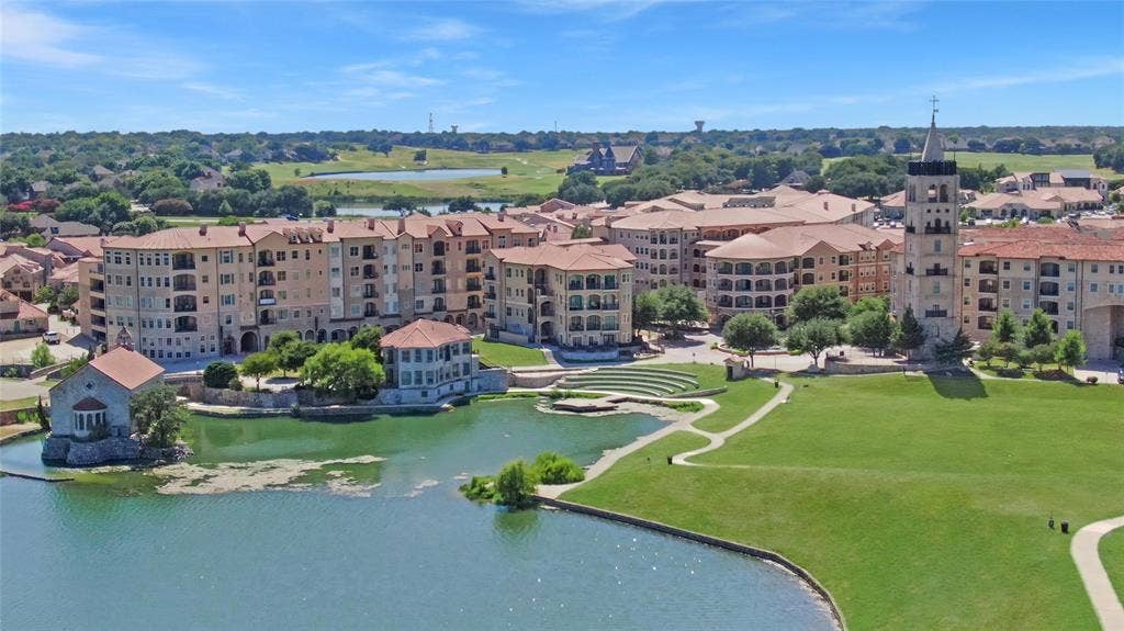 6601 Mediterranean Drive, #6101, McKinney, TX 75072 Waterfront community featuring multi-story buildings with balconies, a prominent bell tower, and a manicured green space