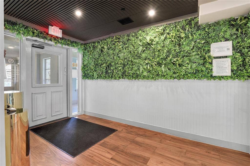 6601 Mediterranean Drive, #6101, McKinney, TX 75072 Entryway featuring a decorative green wall, white wainscoting, wood-finish flooring, and a black slatted ceiling