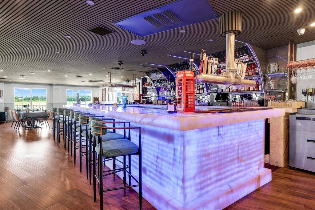 6601 Mediterranean Drive, #6101, McKinney, TX 75072 Illuminated bar with multiple taps and bottle storage, featuring an elongated countertop with seating for multiple patrons