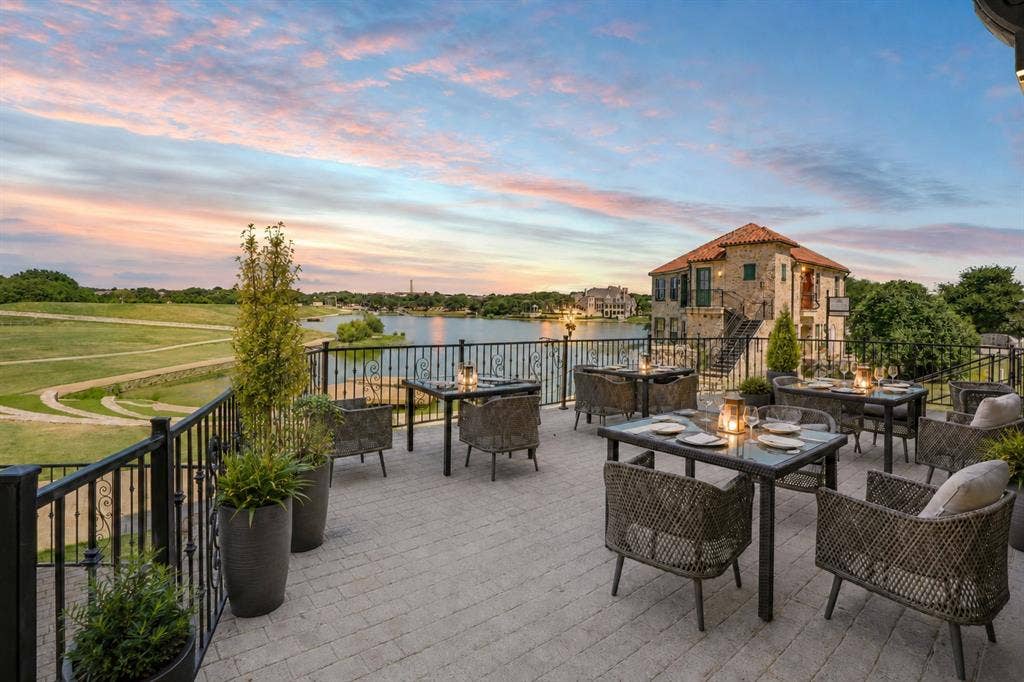 6601 Mediterranean Drive, #6101, McKinney, TX 75072 Expansive outdoor patio featuring paver flooring, a black wrought iron railing, and a serene lake backdrop
