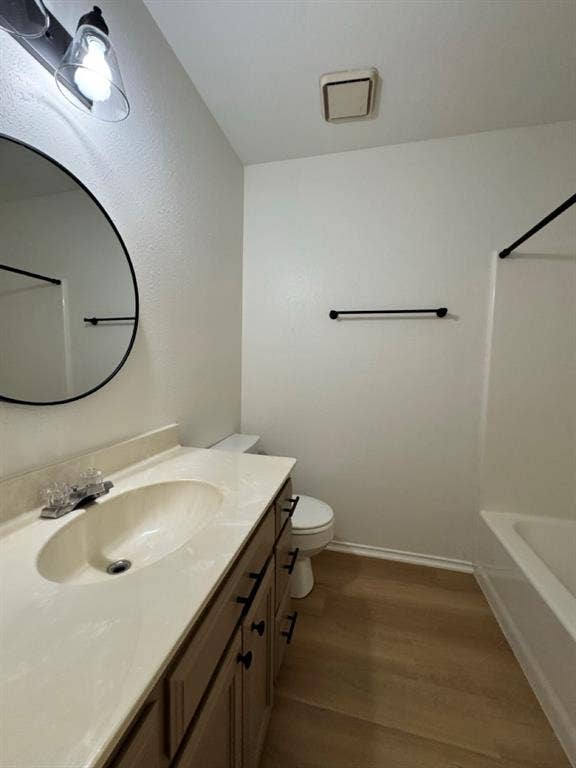 2812 Howard Court, Denton, TX 76209 Bathroom featuring a light-toned vanity with an integrated sink, a circular mirror, and a white toilet