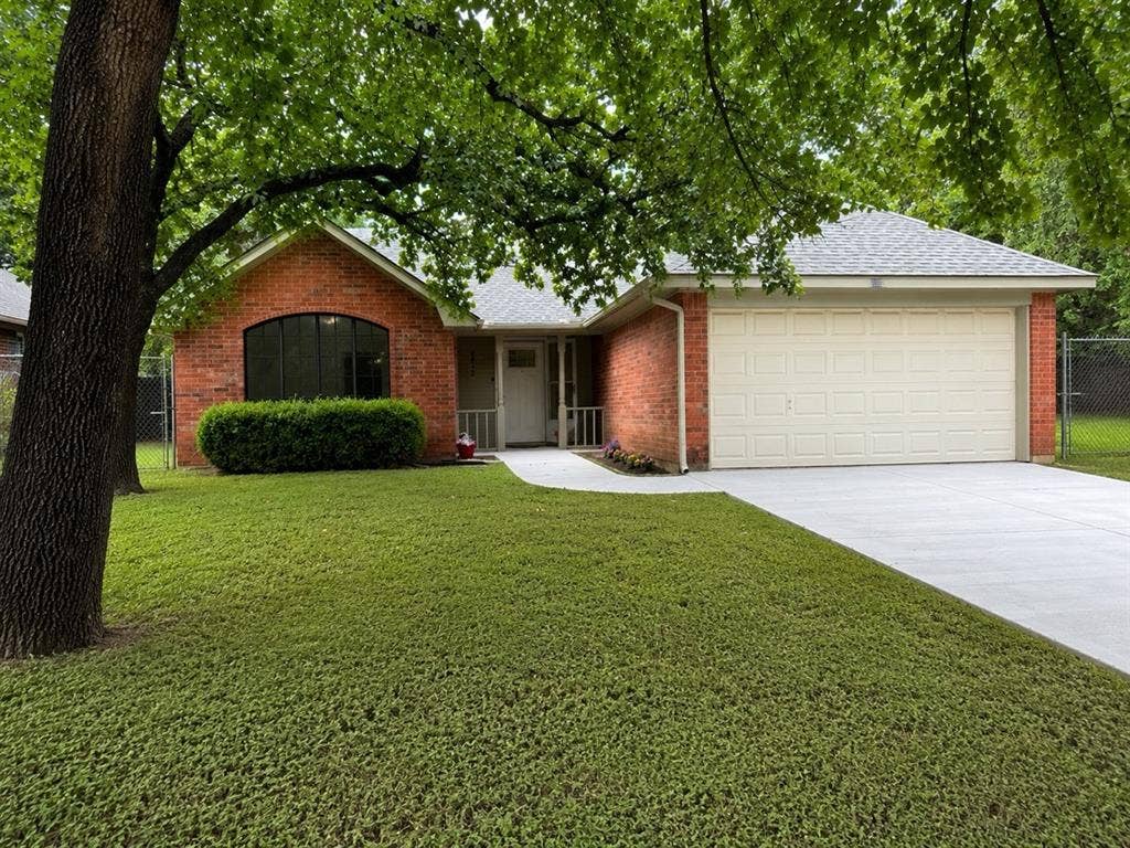 2812 Howard Court, Denton, TX 76209 Brick exterior featuring an arched window, a two-car garage, a concrete driveway, and a front walkway