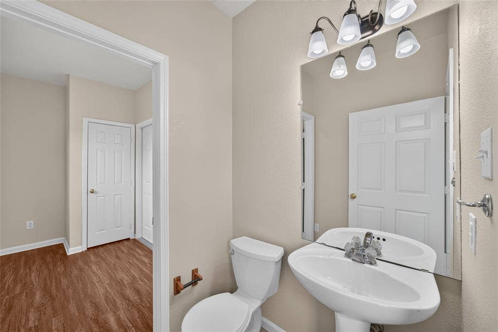 18723 Sims Lane, Nevada, TX 75173 Bathroom featuring a pedestal sink with chrome faucet, a standard toilet, and a five-light vanity fixture