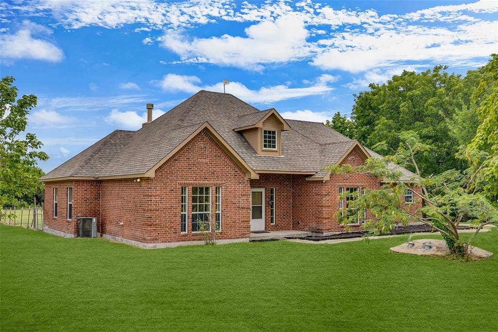 18723 Sims Lane, Nevada, TX 75173 Brick exterior featuring a gabled roofline, dormer window, and mature landscaping