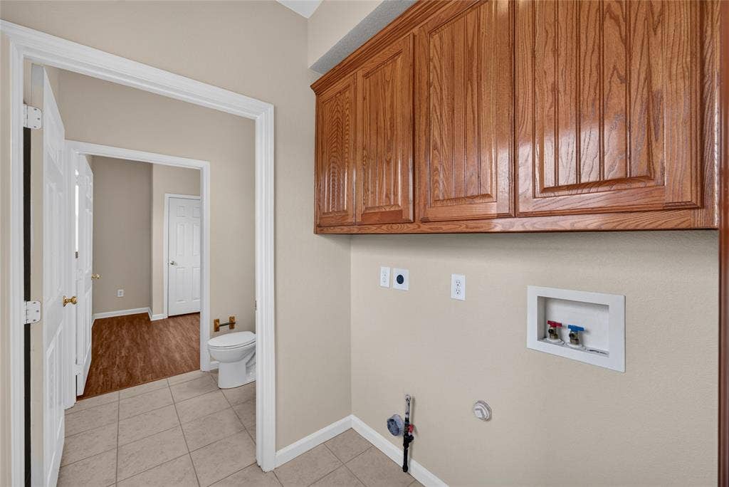 18723 Sims Lane, Nevada, TX 75173 Utility area with wood-finish cabinetry, neutral wall paint, and tiled flooring
