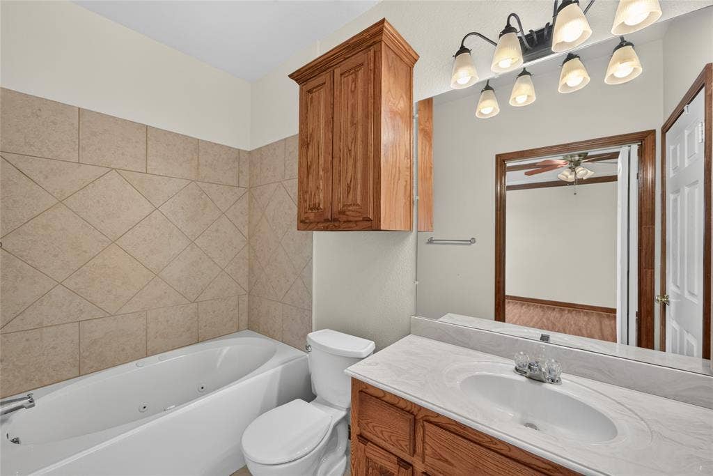 18723 Sims Lane, Nevada, TX 75173 Bathroom featuring a white jetted tub, ceramic tile surround, and a toilet