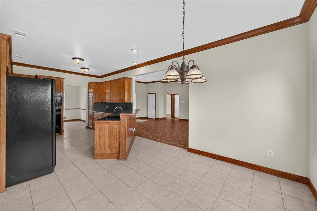 18723 Sims Lane, Nevada, TX 75173 Kitchen and dining area featuring light-toned tile flooring and a bronze chandelier
