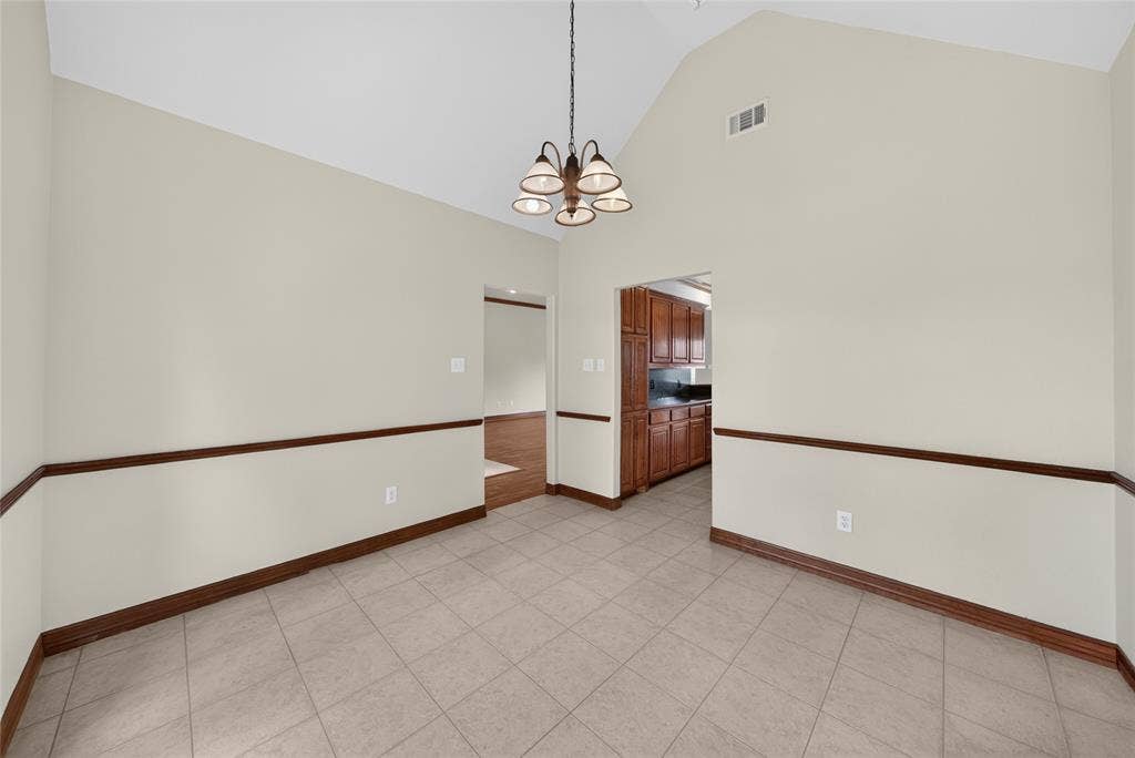 18723 Sims Lane, Nevada, TX 75173 Vaulted ceiling dining area featuring neutral wall tones, decorative chair rail molding, and tile flooring