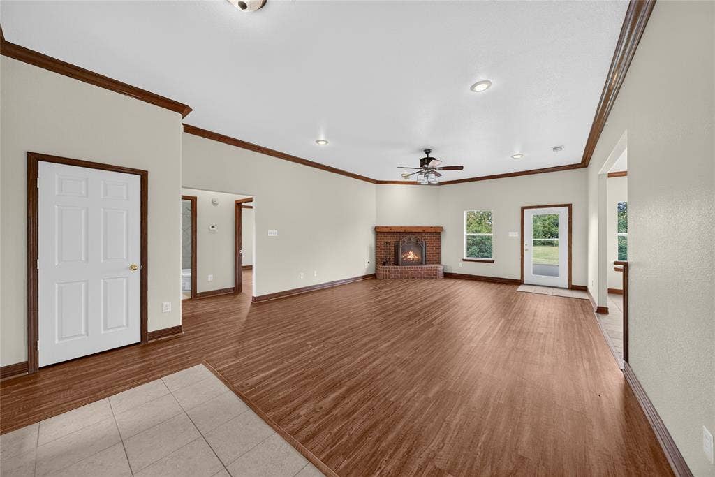 18723 Sims Lane, Nevada, TX 75173 Spacious living area featuring wood-finish flooring, a brick fireplace, recessed lighting, a ceiling fan, and crown molding accents