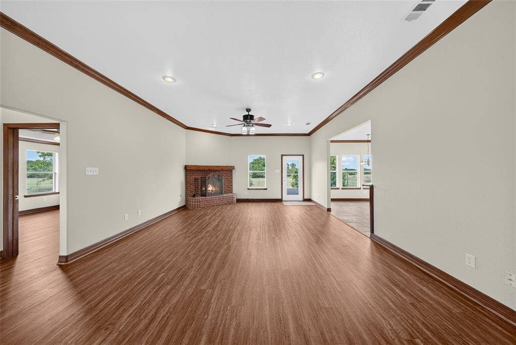 18723 Sims Lane, Nevada, TX 75173 Spacious interior featuring wood-finish flooring throughout, a brick fireplace with a hearth, multiple windows, recessed lighting, and a ceiling fan